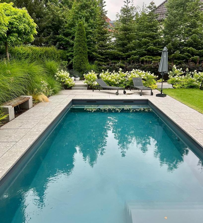 Swimmingpool und Hortensienbepflanzung im modernen Familiengarten.